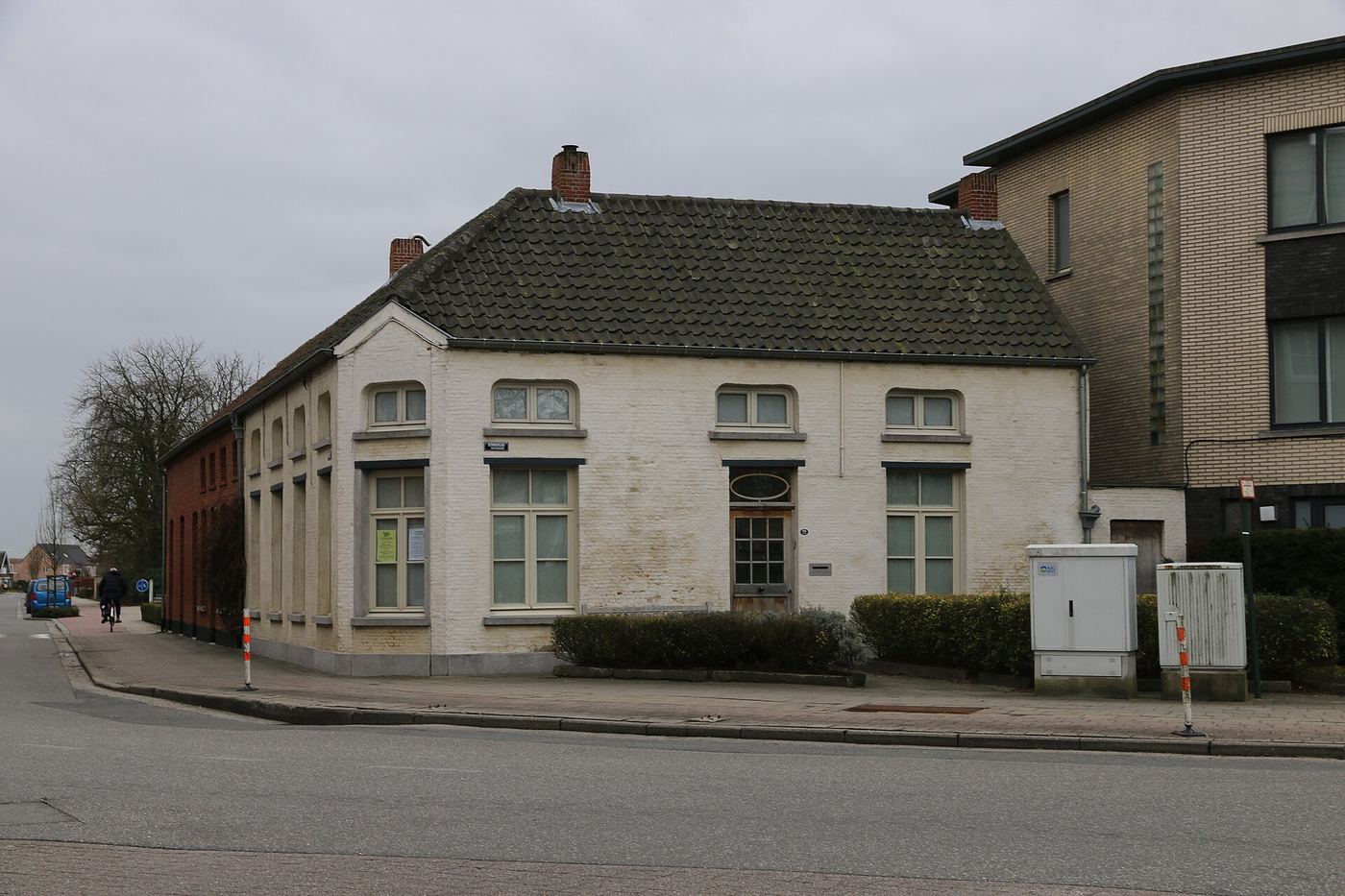 Wit gepleisterd en geschilderd dorpshuis op een hoek in Koningshooikt