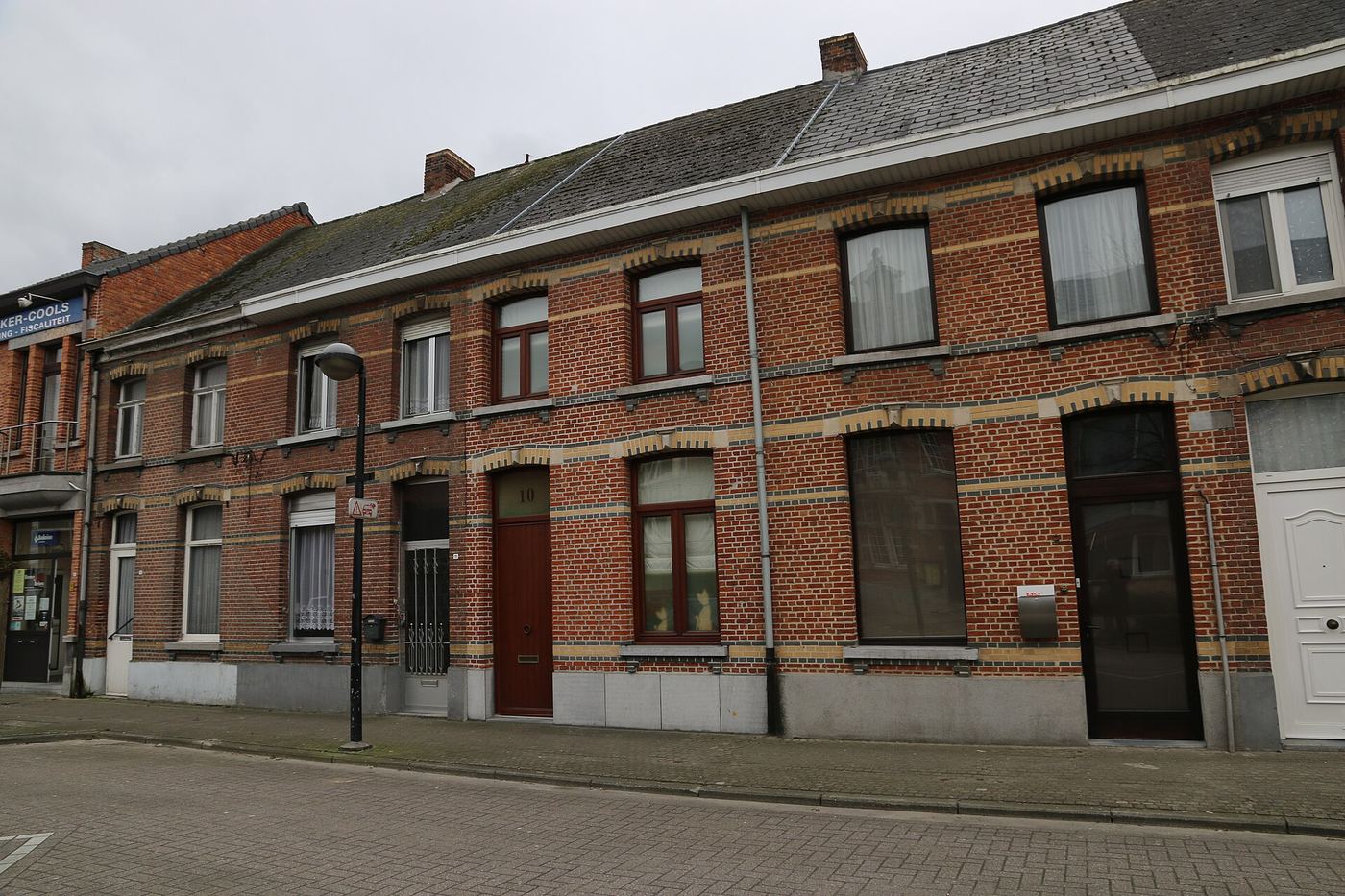 Rij bakstenen dorpswoningen met witte banden in een straat in Koningshooikt
